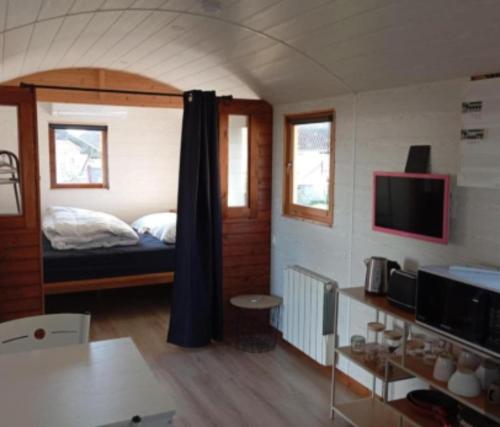 a bedroom with a bed and a tv in a room at roulotte en bois in Ranton