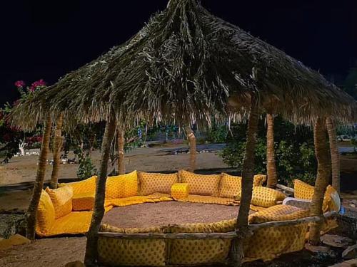 a couch under a straw umbrella on the beach at منتجع سفاري ديور in At Turbīyah