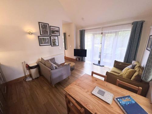 a living room with two couches and a table at Beech Lodge Cottage in Blagdon