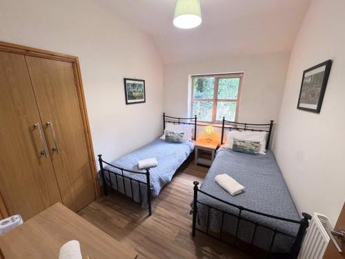 two beds in a small room with a door at Beech Lodge Cottage in Blagdon