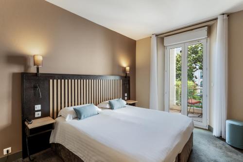 a bedroom with a large bed and a large window at Hotel Molière in Cannes