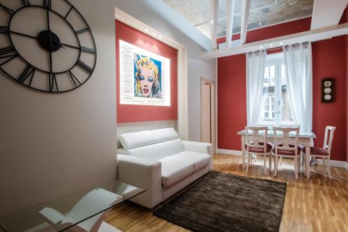 a living room with a white couch and a clock on the wall at Apart Hotel Torino in Turin