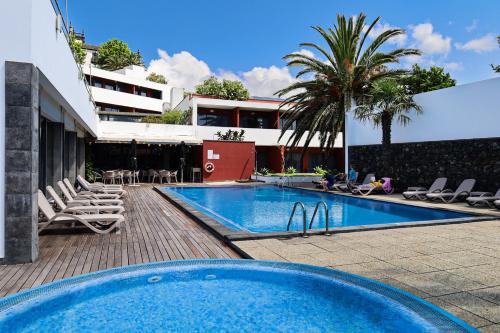 a swimming pool with chairs next to a building at Antillia Hotel in Ponta Delgada