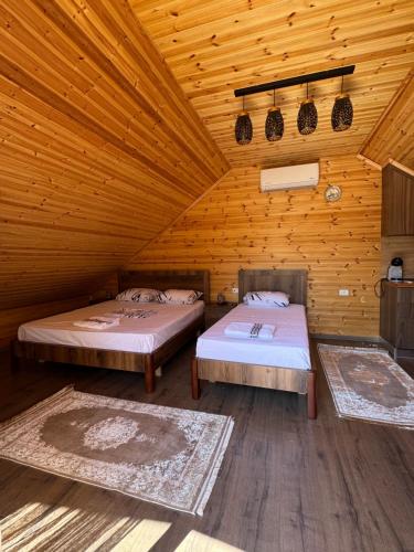 two beds in a wooden room with wooden ceilings at Naimi in Pukë