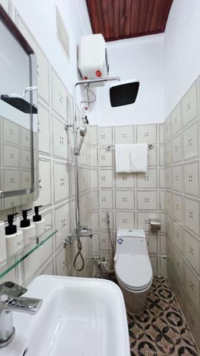 a bathroom with a toilet and a sink and a mirror at Mật Ong HOUSE in Hue