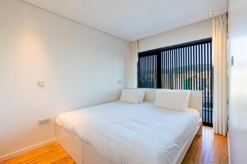 a white bed in a room with a large window at Moledo Front Beach by Portugal Active in Viana do Castelo