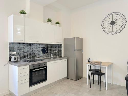 a kitchen with white cabinets and a table and a refrigerator at Demetra Apartment in Bologna