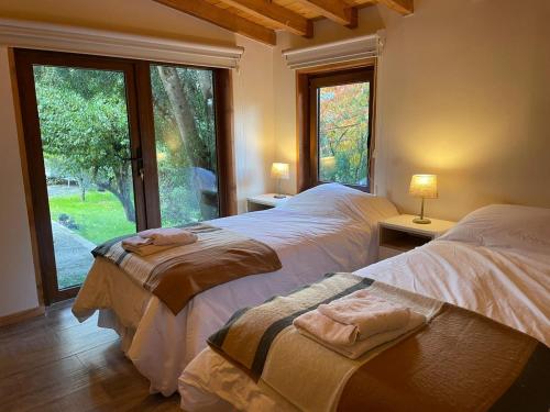 a bedroom with two beds and a large window at Green House B & B in Villa La Angostura