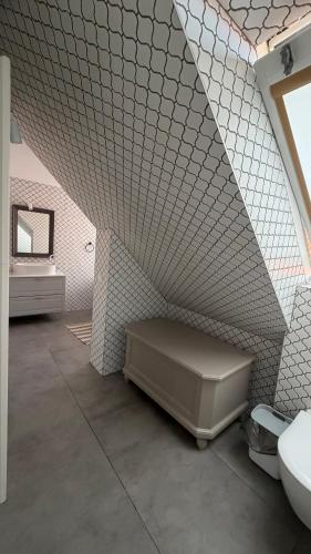 a bathroom with a white tiled wall and a sink at Lotmiškio 1 in Neringa