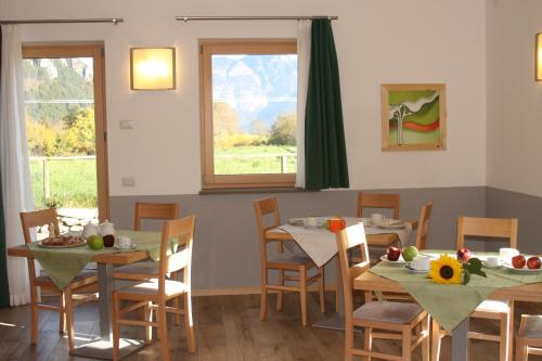 ein Esszimmer mit Tischen, Stühlen und einem Fenster in der Unterkunft Agriturismo Girasole in Fai della Paganella