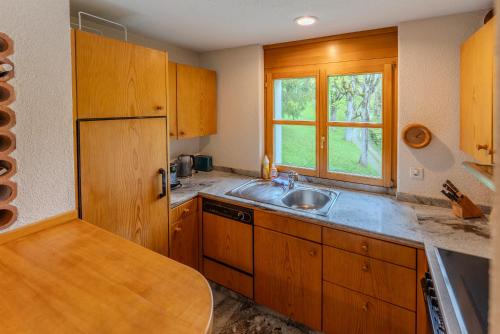 a kitchen with wooden cabinets and a sink and a window at Charmante Wohnung im Dorfkern in Klosters