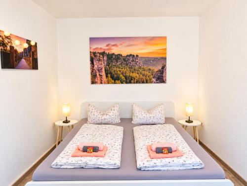 two beds in a room with two lamps and a painting at Urlaubsmagie Ferienwohnung Wiesengrün - direkt am Wanderweg - für 6P - W6 in Sebnitz