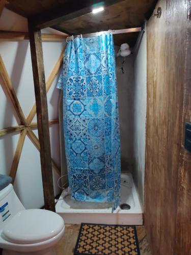 a bathroom with a toilet and a blue shower curtain at Glamping Entre las Nubes in Mineral del Monte