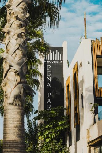 a palm tree in front of a building with a sign at H Boutique Peña Parda in La Herradura