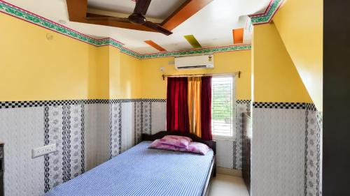 a bed in a room with yellow walls and a window at Hotel Protima guest inn in Digha