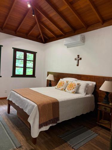 a bedroom with a bed with a cross on the wall at A Casinha Lumiar in Lumiar