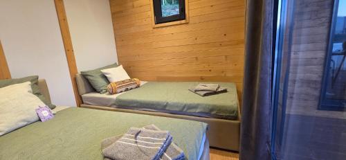 two twin beds in a room with wooden walls at Tiny Merak - Ramsko jezero in Kovačevo Polje