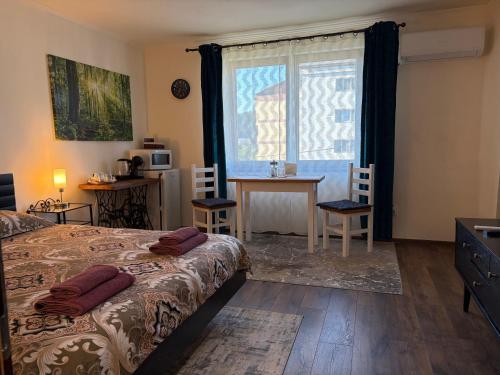 a bedroom with a bed and a table and a window at Alio Room Campulung Moldovenesc in Câmpulung Moldovenesc