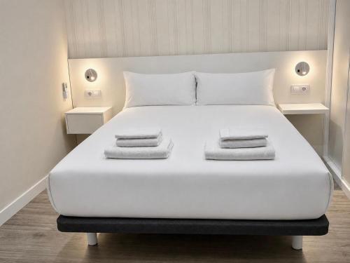 a large white bed with two towels on it at O Lar de LUCI in Nigrán