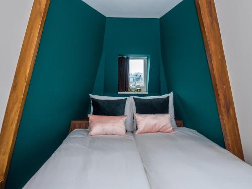 a bed with two pink pillows in a blue room at Linden Hotel in Amsterdam