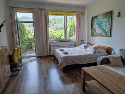 a bedroom with two beds and a couch and a window at Zielona Przystań Apartament z widokiem na Pieniny in Jaworki