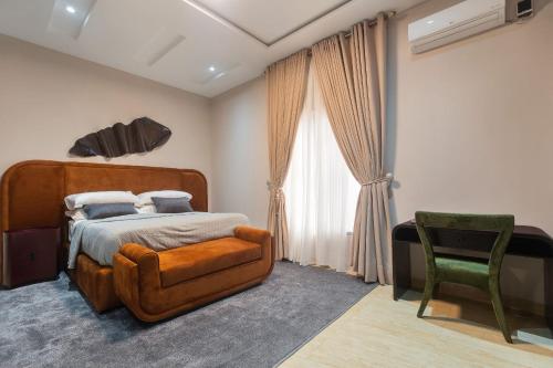a bedroom with a bed and a green chair at Yaniv Apartments Oniru in Lagos