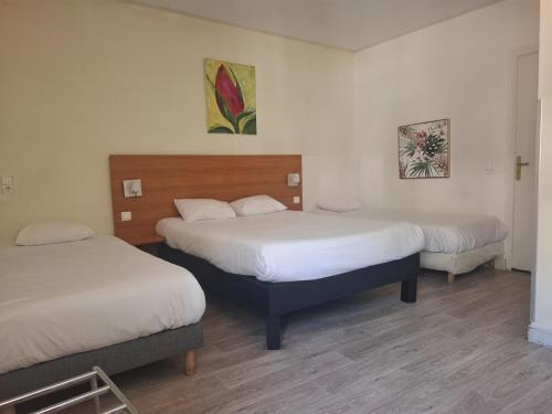 a hotel room with two beds and two paintings on the wall at Hôtel de Paris - Dijon Centre Gare in Dijon
