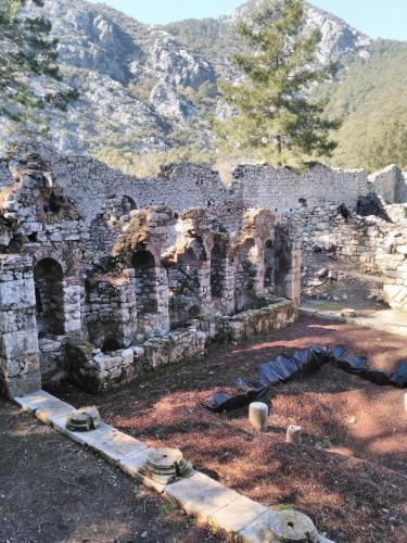 an old stone building with a mountain in the background at Bahçe Villa in Cıralı