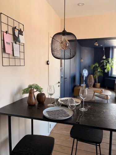 a dining table with two wine glasses and aendant light at Au pied du mur in Huy