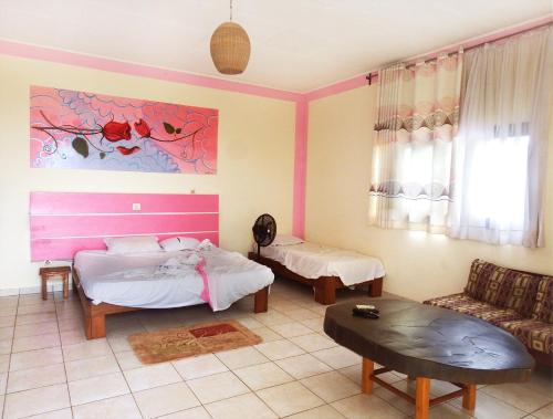 a bedroom with two beds and a table and a couch at BEAUSÉJOUR Plage in Kribi