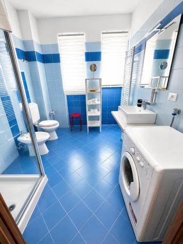Grab a Flat in Coroneo في ترييستي: حمام أزرق اللون مزود بغسالة ملابس