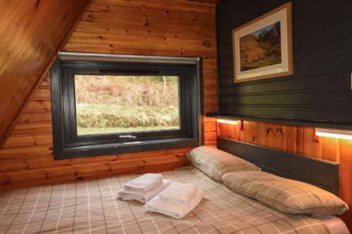 a room with a window and two towels on a bed at 1 Bedroom Cabin with Mountain & Loch Views - Quiet Location between Glencoe & Ben Nevis in Corran