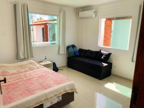 a bedroom with a bed and a couch and windows at Vila Bangalô in São José da Coroa Grande