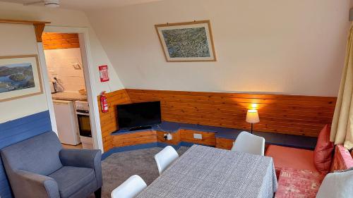 a room with a table and a television and a table and chairs at 1 Bedroom Cabin with Mountain & Loch Views - Quiet Location between Glencoe & Ben Nevis in Corran