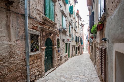 an alley in an old town with stone buildings at Apartments Aalvar and Aalto in Rovinj