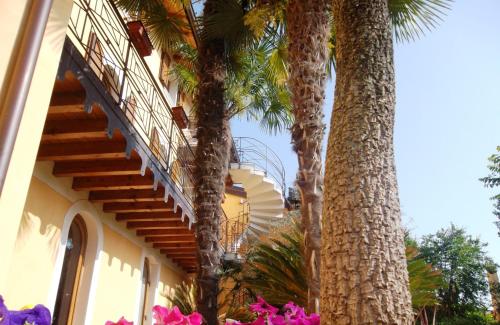 a building with palm trees next to a staircase at Albergo Le Piante in Manerba del Garda