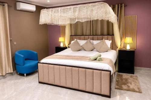 a bedroom with a large bed and a blue chair at KJ Apartments in Lilongwe