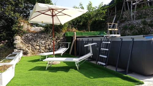 a patio with two chairs and an umbrella and a ladder at Casale Gelsi in Maiori
