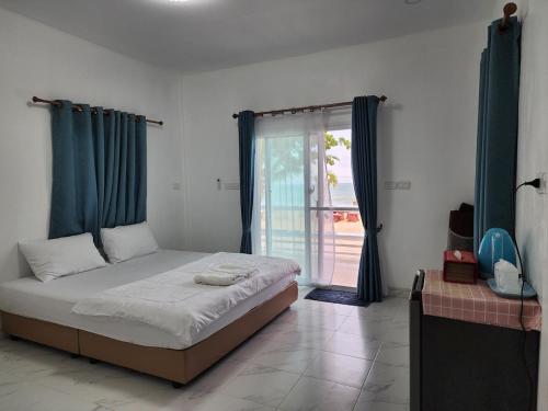 a bedroom with a bed and a large window at Chomlay House in Ban Thepha