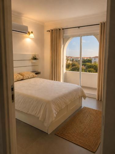 a bedroom with a bed and a large window at ENJOY POOL, BEACH and more at this nice 2bedroom apartment only 3 minutes from Mareta's Beach in Sagres