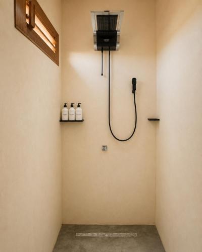 a shower in a room with three bottles on the wall at The Wave Kite House in Guriú