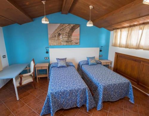 two beds in a room with blue walls at La Casona De Cuellar in Cuéllar