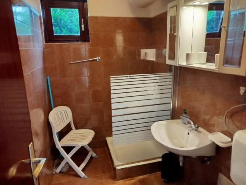 a bathroom with a chair and a sink at Apartment Hribar 2 in Ravni