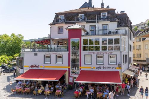 Eine Gruppe von Menschen sitzt an Tischen vor einem Gebäude in der Unterkunft Hotel La Baia in Cochem