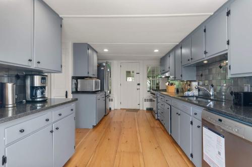 a large kitchen with white cabinets and wooden floors at Featured in Cape Cod Life Magazine in Barnstable