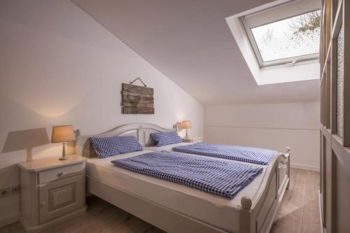 a white bedroom with a bed and a window at Bergschlössl - Massionettwohnung 13 in Oberaudorf