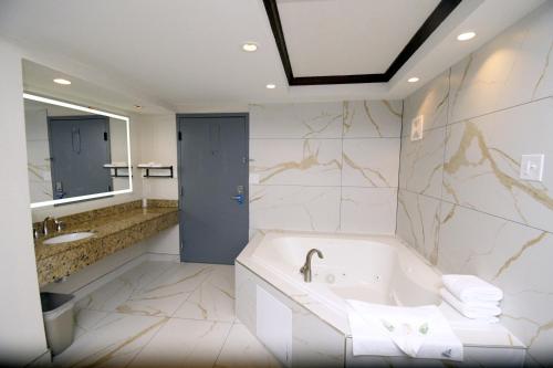a bathroom with a tub and a sink and a mirror at Rodeway Inn & Suites East Windsor in East Windsor