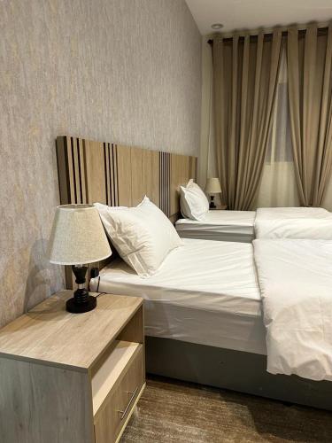 a bedroom with two beds and a table with a lamp at فندق أوريون orion hotel in Al-ʿUla
