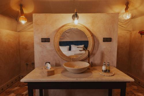 a bathroom with a sink and a mirror at Tassili Luxury Desert Camp in Merzouga