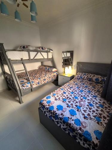 a bedroom with two bunk beds with blue flowers at Royal Green Haven 3BR Apartment near Airport Obour in Obour